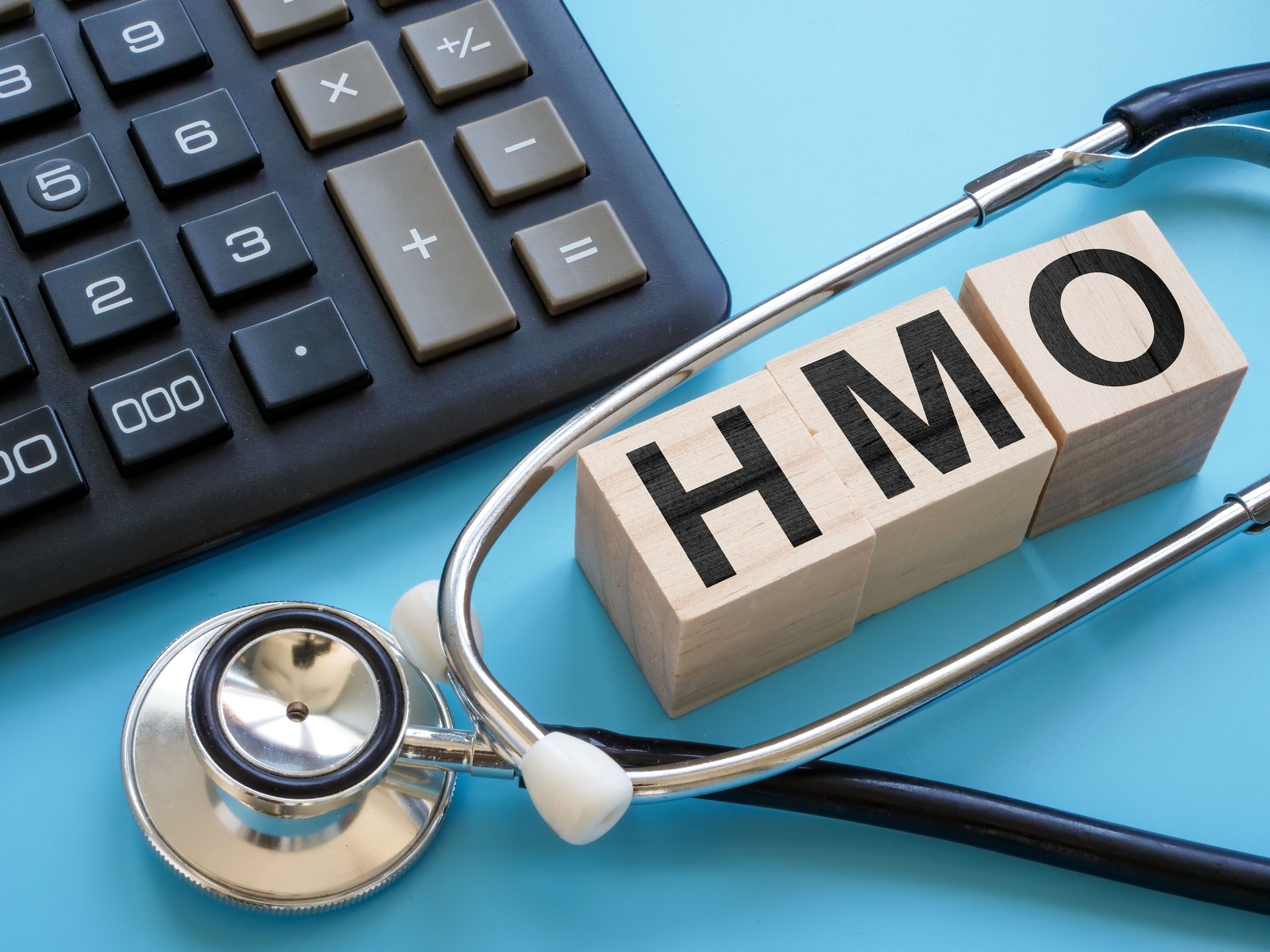 Stethoscope and cubes with letters HMO Health Maintenance Organization insurance.